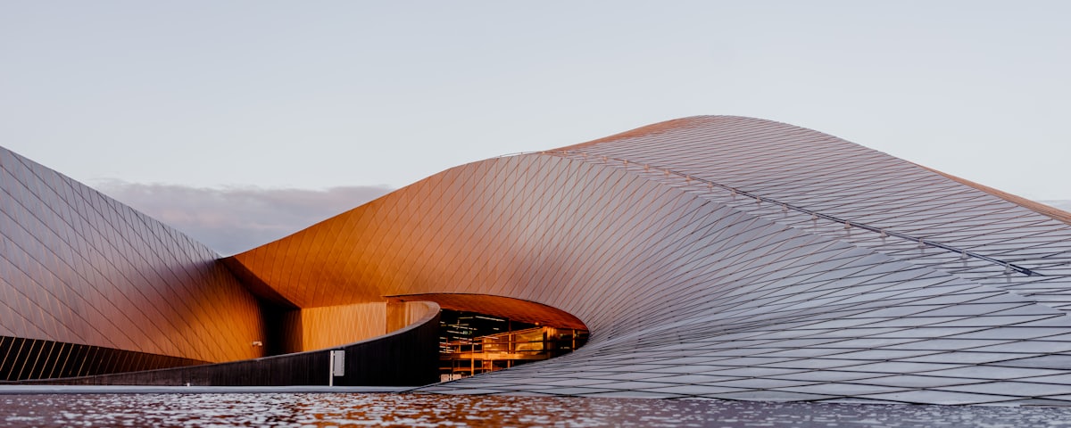 A calm modern building with a curved form beside still water